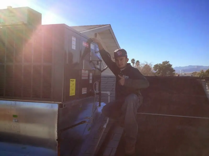 HVAC technician performing Air Duct Cleaning on a rooftop unit in White Oak